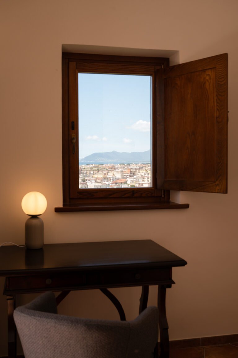 Vista dalla finestra della Camera Petra nella guest house Vicolo Effe, con lampada e scrivania in primo piano